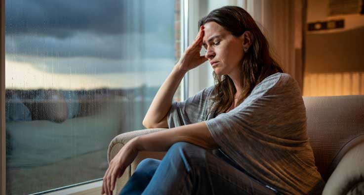 ქალი აივანზე, რომელიც თავს ცუდად გრძნობს ამინდის ცვალებადობის გამო - მეტეოდამოკიდებულება